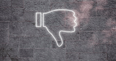 Composite of illuminated digital white dislike button icon against gray wall, copy space. Thumbs down, social media, negative emotion, hand, symbol and feedback concept.の写真素材