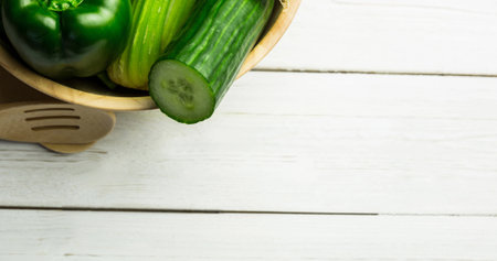 High angle view of fresh green bell pepper, cucumber and chinese cabbage bowl and spoon on table. Copy space, unaltered, veganism, organic, food, healthy, support, vegan day and celebration.の写真素材