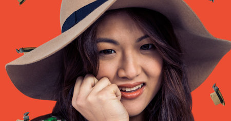 Close-up portrait of smiling young asian woman wearing hat with digital headwear. Digital composite,...