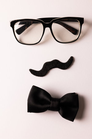 Composition of fake moustache with glasses and bow tie on white background with copy space. Fake moustache day, party, celebration and costume concept.の写真素材
