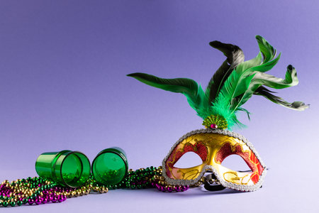 Composition of colourful mardi gras beads, shot glasses and carnival mask, on blue with copy space. Party, celebration and carnival concept.の写真素材