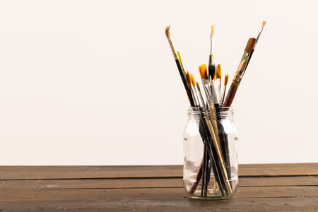 Composition of jar of painting brushes on white background. National craft month, painting, art and copy space, digital composite image.の写真素材