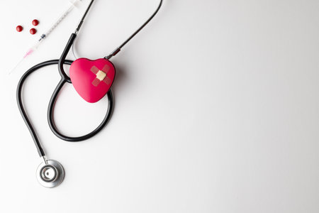 Composition of stethoscope, heart and sticking plasters, syringe and pills, on white with copy space. Medical services, healthcare and health awareness concept.の写真素材