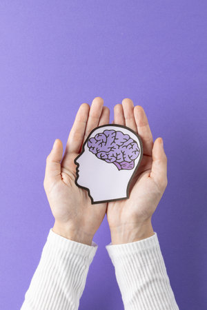 Composition of hands holding head silhouette with brain on purple background. Medicine, healthcare, science and copy space concept, digital composite image.の写真素材