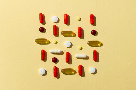 Composition of a variety of pills and capsules on yellow background with copy space. Medicine, medical services, healthcare and health awareness concept.の写真素材