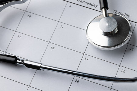 Close up, full frame composition of stethoscope on calendar. Medical services, healthcare and health awareness concept.の写真素材