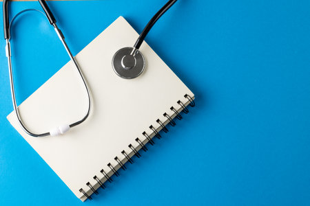 Composition of stethoscope with notebook on blue background with copy space. Medical services, healthcare and health awareness concept.の写真素材