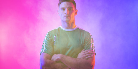 Portrait of caucasian male player with arms crossed standing against pink and blue background. Copy...