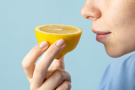 Close up of caucasian woman holding lemon on blue background. Medicine, healthcare and science...