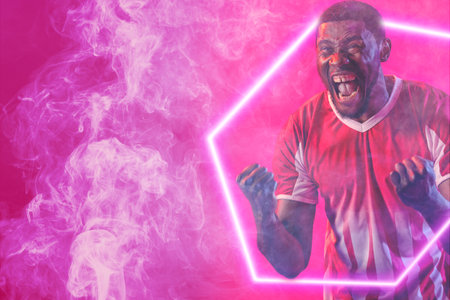 African american male soccer player screaming on smoky pink background, copy space. Achievement, happy, composite, sport, soccer, competition, neon, illustration, glowing and abstract.の写真素材
