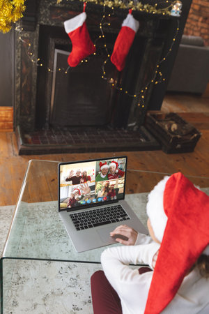 Caucasian woman having christmas video call with diverse people. Communication technology and christmas, digital composite image.の写真素材