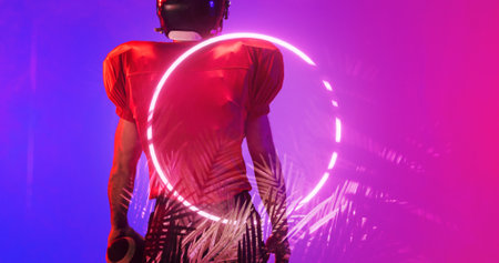 Rear view of american football player wearing red uniform standing by illuminated circle and plants. Copy space, composite, sport, competition, illustration, glowing, nature, shape, abstract concept.の写真素材