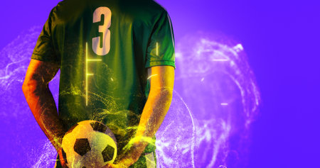 Rear view of soccer player holding ball with abstract neon in blue background, copy space. Computer graphic, copy space, digital composite, soccer, design, athlete, competitive sport.の写真素材