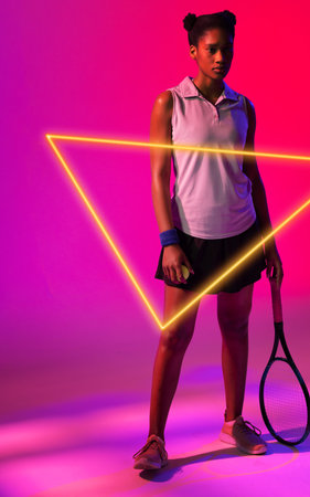 African american female player holding ball and racket by illuminated triangle on pink background. Copy space, tennis, composite, sport, competition, shape, match and abstract concept.の写真素材