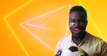 African american soccer player with english flag's face paint holding ball by geometric shapes....