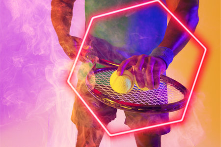 Midsection of african american male tennis player placing balls on racket by illuminated hexagon. Copy space, composite, sport, shape, hand, smoke, competition, playing, match and abstract concept.の写真素材