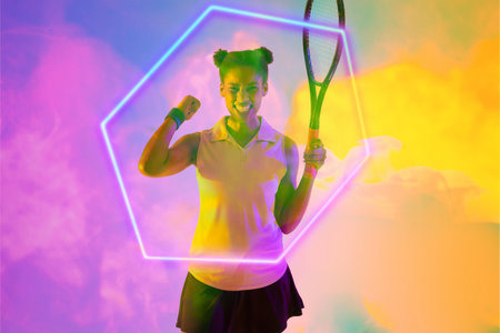 Excited african american female tennis player holding racket shaking fist by illuminated hexagon....