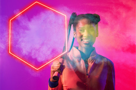 Happy african american female player with tennis racket by hexagon on smoky colored background. Copy...