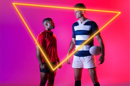 Diverse male opponents looking at each other with ball by illuminated triangle over pink background....