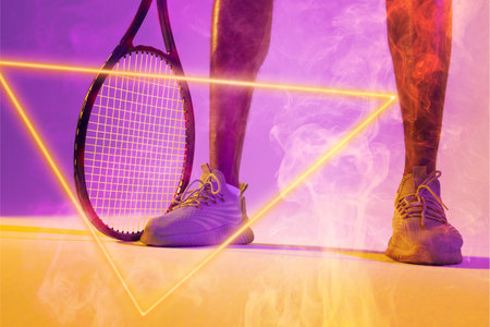 Low section of african american male tennis player wearing white shoes with racket by triangle. Copy space, composite, sport, shape, illuminated, competition, smoke, match and abstract concept.の写真素材