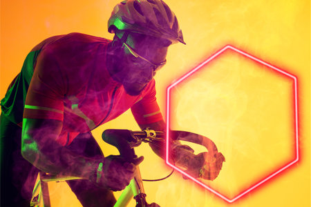African american male cyclist wearing glasses and helmet riding bike by illuminated hexagon. Copy space, composite, sport, cycling, racing, competition, yellow, shape and abstract concept.の写真素材
