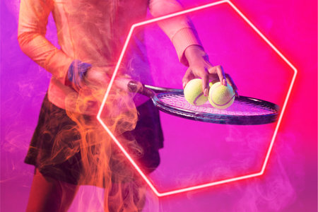 Midsection of african american female tennis player placing balls on racket by illuminated hexagon. Copy space, composite, sport, shape, competition, hand, playing, match and abstract concept.の写真素材