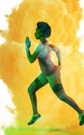 Side view of african american female athlete with afro hair running over yellow smoky background....