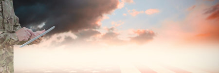 Composition of caucasian soldier using tablet over clouds with copy space. Global science, celebration and sport concept digitally generated image.の写真素材