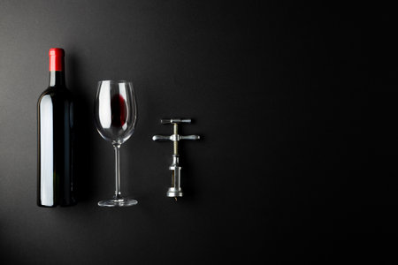 Bottle of red wine, glass and corkscrew on black background, with copy space. Wine week, drink and celebration concept.の写真素材