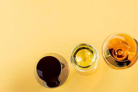 Glasses with red, rose and white wine on yellow background, with copy space. Wine week, drink and celebration concept.の写真素材