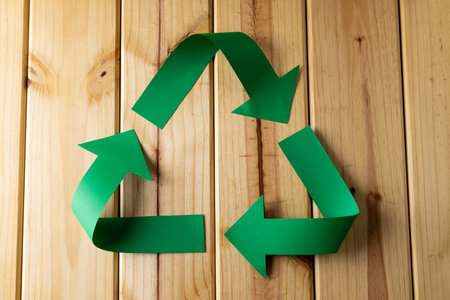 Close up of recycling symbol of paper green arrows on wooden background with copy space. Global ecology and recycling concept.の写真素材