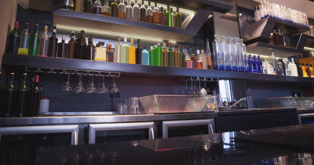 Image of rows of bottles on shelves in bar. National beer day concept digitally generated image.