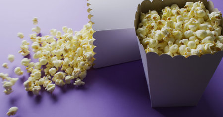 Image of close up of two white popcorn tubs on purple background. Popcorn, snacks and fast food concept.の写真素材