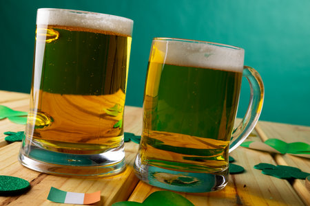 Image of beer glasses, clover and flag of ireland on wooden background. St patrick&#39;s day, irish tradition and celebration concept.の写真素材