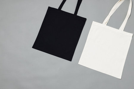 High angle view of black and white canvas bags with copy space on grey background. Bags and fashion concept.の写真素材