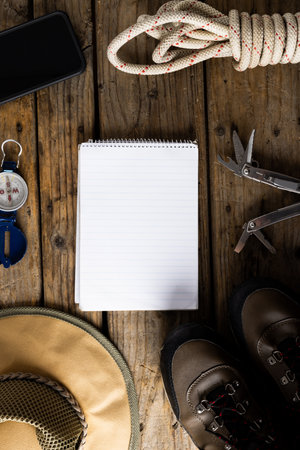Camping equipment, smartphone and blank notebook on wooden background with copy space. National camping month, equipment and celebration concept.の写真素材