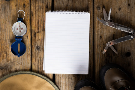 Camping equipment of compass, pocket knife and blank notebook on wooden background with copy space. National camping month, equipment and celebration concept.の写真素材