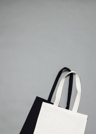 High angle view of black and white canvas bags with copy space on grey background. Bags and fashion concept.の写真素材