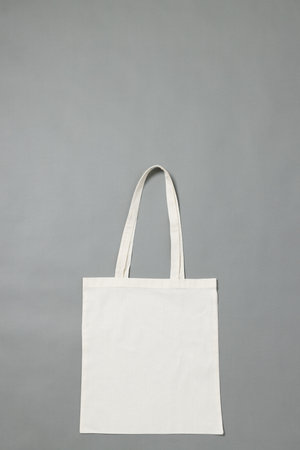 High angle view of white canvas bag with copy space on grey background. Bags and fashion concept.