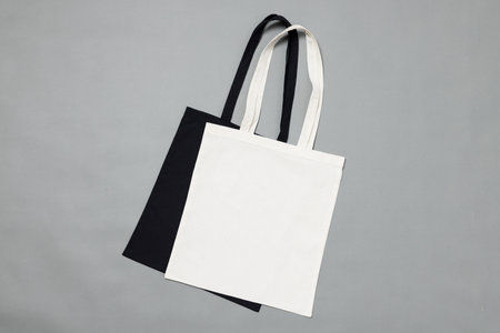 High angle view of black and white canvas bags with copy space on grey background. Bags and fashion...