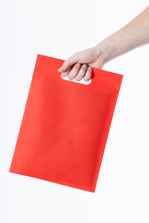 Hand of caucasian woman holding red bag with copy space on white background. Bags and fashion concept.の写真素材
