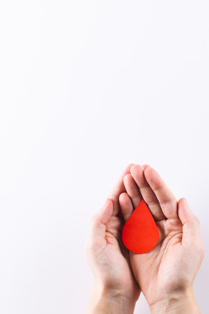 Hands of caucasian woman cupping blood drop, on white background with copy space. Blood donation, medicine and healthcare.の写真素材