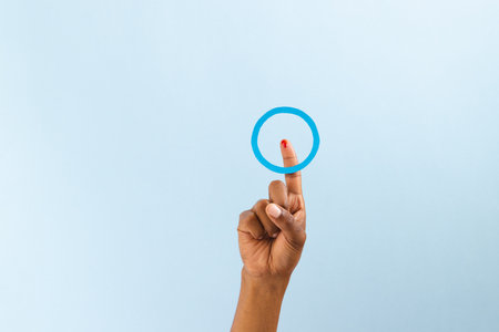 Hand of biracial man with blue ring over bleeding finger, on blue background with copy space. Blood sugar, diabetes and health awareness.の写真素材