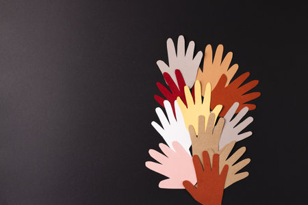 Paper cut out of multi coloured hands with copy space on black background. Humanitarian aid, people, help and human concept.の写真素材