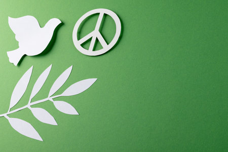 Close up of white dove and peace sign with leaves and copy space on green background. Peace and anti war movement concept.の写真素材