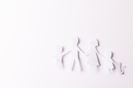 White paper cut out of family with two children and cat and copy space on white background. Humanitarian aid, people, help and human concept.の写真素材