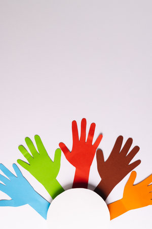Paper cut out of multi coloured hands and white circle with copy space on white background. Humanitarian aid, people, help and human concept.の写真素材