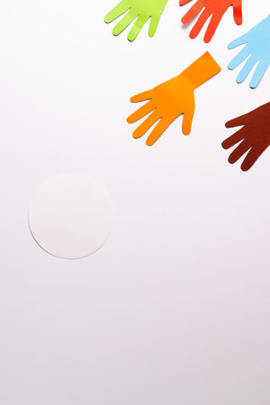 Paper cut out of multi coloured hands and white circle with copy space on white background. Humanitarian aid, people, help and human concept.の写真素材