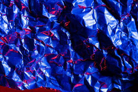 Close up of crumpled shiny blue and red foil with copy space. Colour, texture and material.の写真素材
