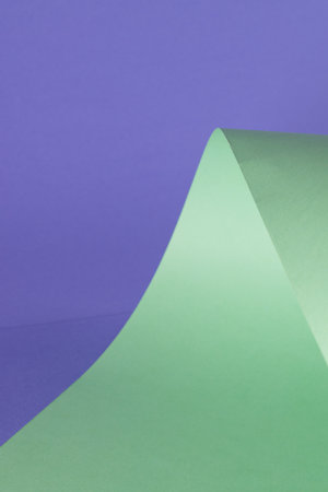 Close up of green paper on purple background with copy space. Colour, texture and material.